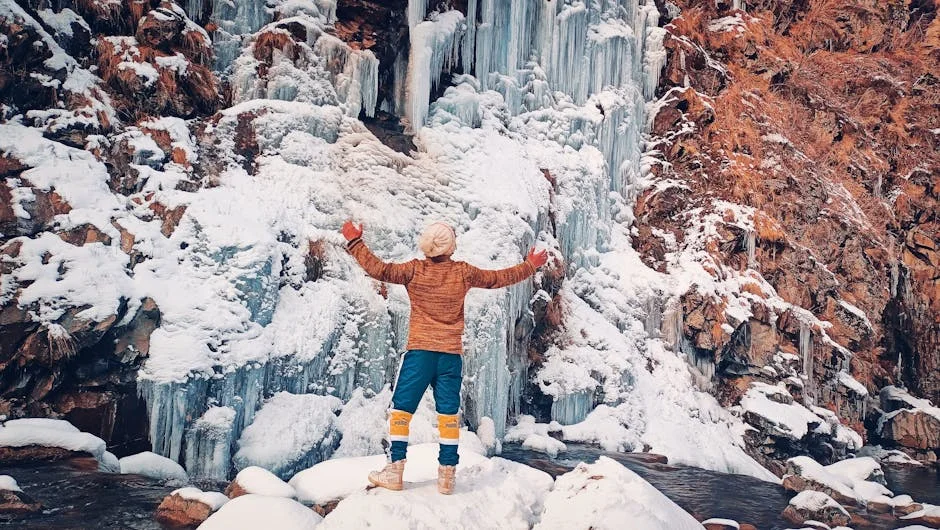 Ricketts Glen Winter Hiking: Frozen Falls Guide (2026) 2 Person stands before majestic frozen waterfall with arms outstretched in wonder