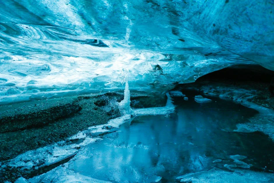 Blue ice cave interior with reflective frozen waters creating mirror-like surface