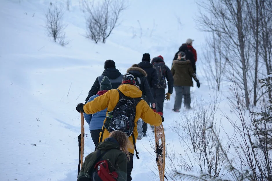 A group of people snowshoeing uphill together on a snowy mountain slope