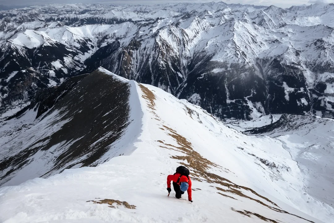 Mountaineer climbing snow-covered slope demonstrating proper winter hiking technique
