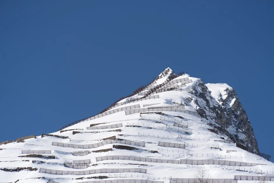Snow-covered mountain peak with avalanche barriers showing winter hazard terrain