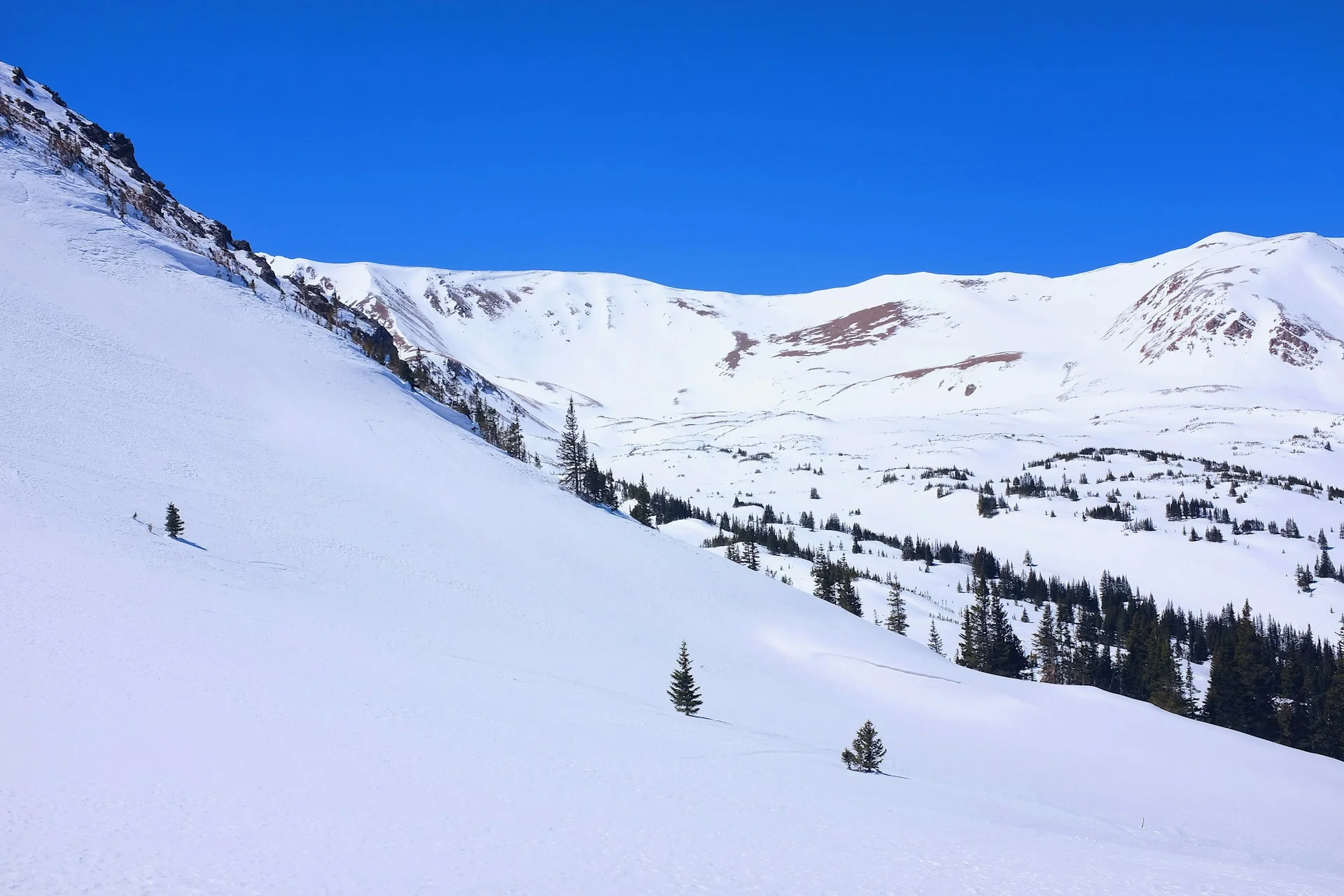 Snow covered mountain vista under blue sky at Rocky Mountain National Park