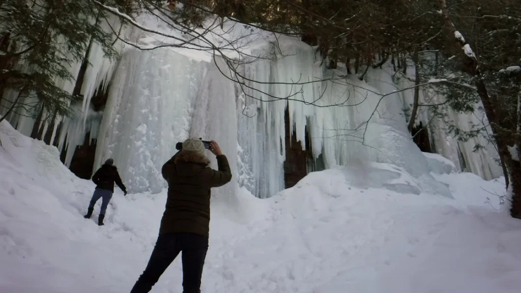 Pictured Rocks snowshoeing January - visitor photographing 20-foot ice curtains at Sand Point