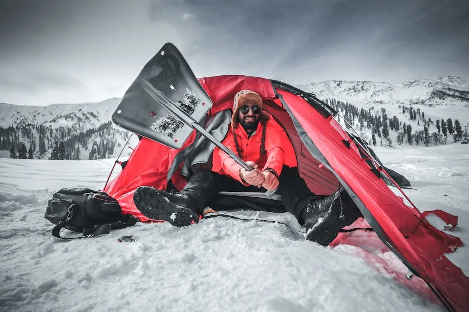 Camper shoveling snow at a winter campsite with packed snow around the area