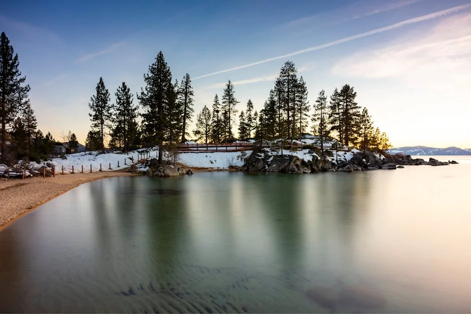 Tranquil winter scene with snowy shores and pine trees at Lake Tahoe during golden hour