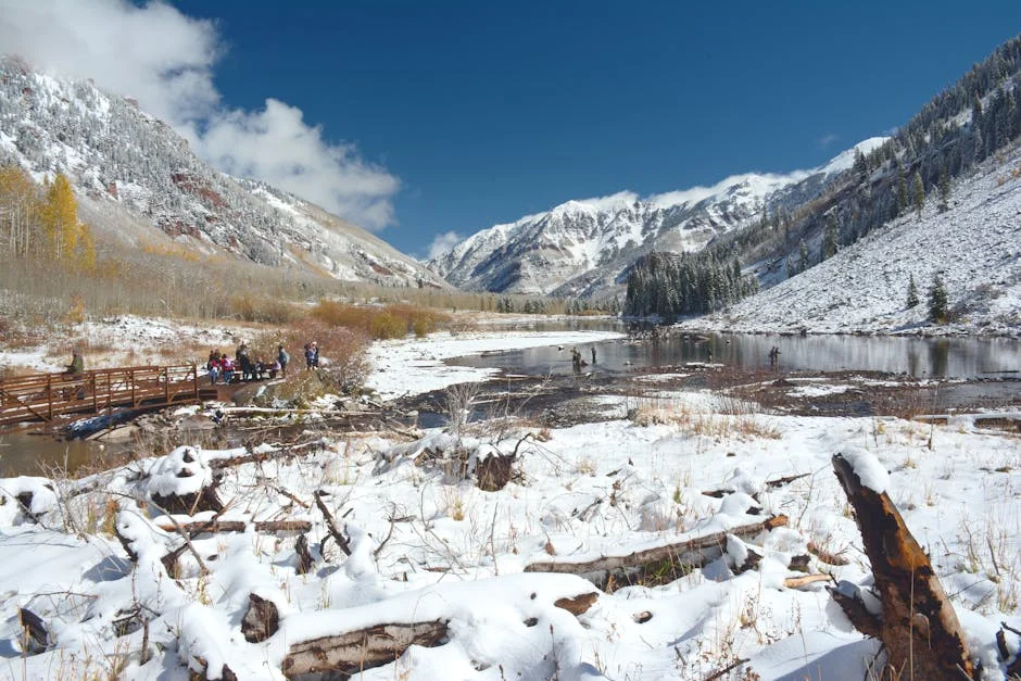 Snow-covered Aspen valley landscape with hikers on a bridge and mountain peaks in background